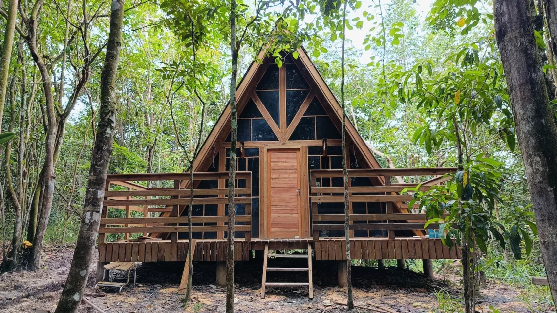 Uma casa de madeira pré-fabricada com deck na floresta, ilustrando as vantagens das casas de madeira.